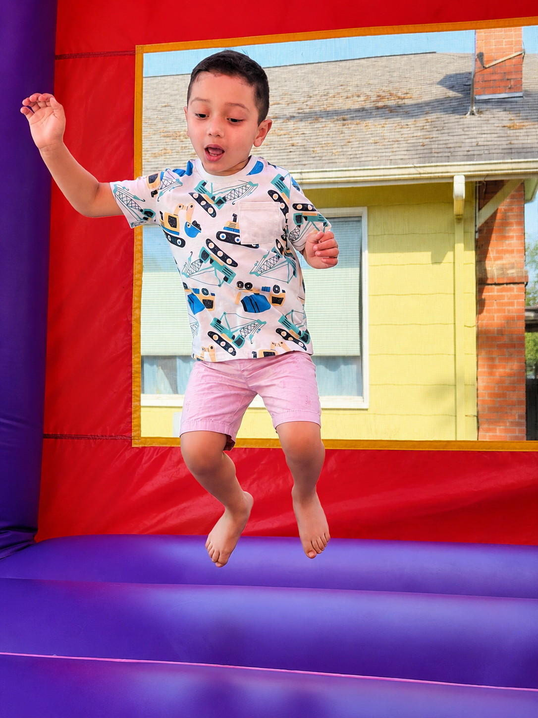 A boy mid-air inside a red and yellow bounce castle.