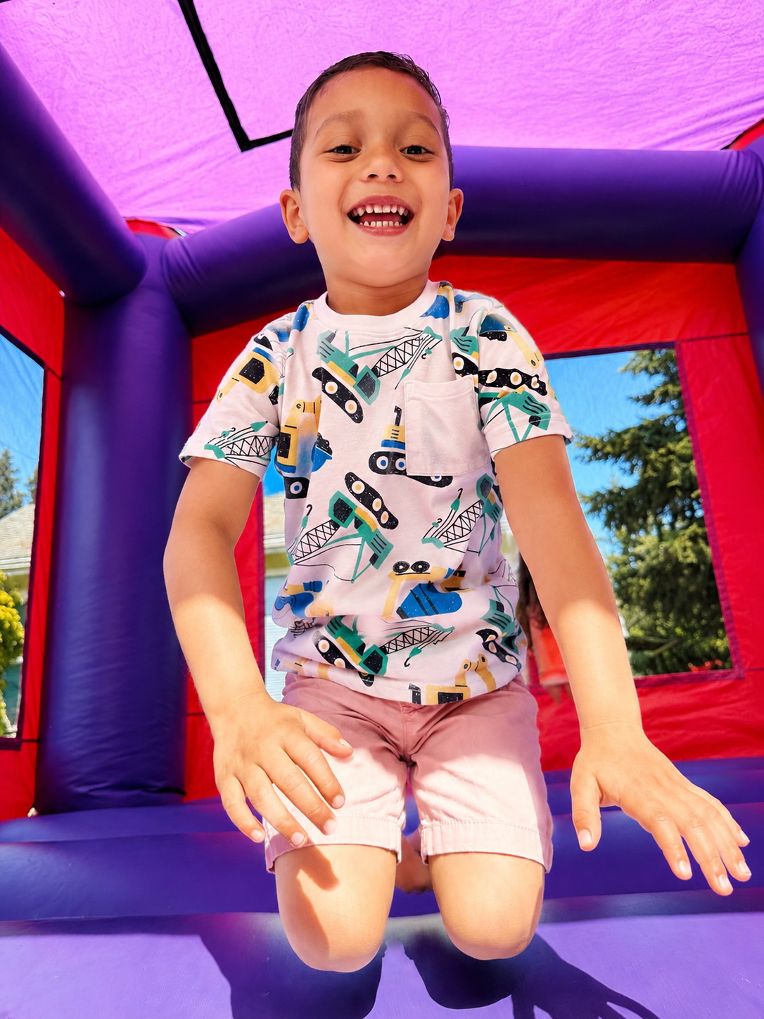 A boy laughing mid-bounce, arms wide.
