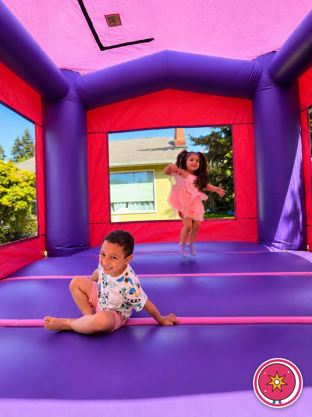 Two children bouncing and laughing inside a Mateo Party Co. bounce house
