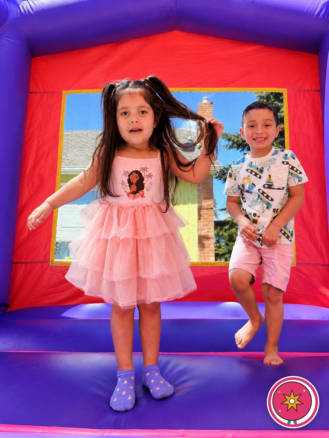 A girl and boy smiling inside a Mateo Party Co. castle bounce house