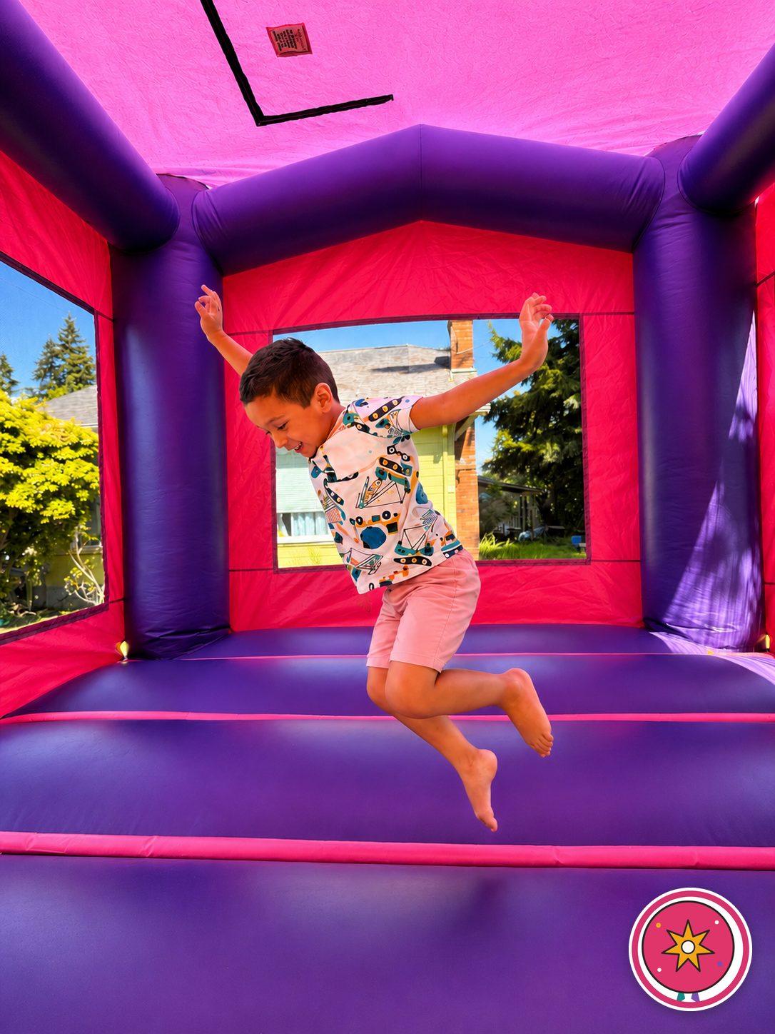 A boy leaping with both arms up inside a Mateo Party Co. bounce house